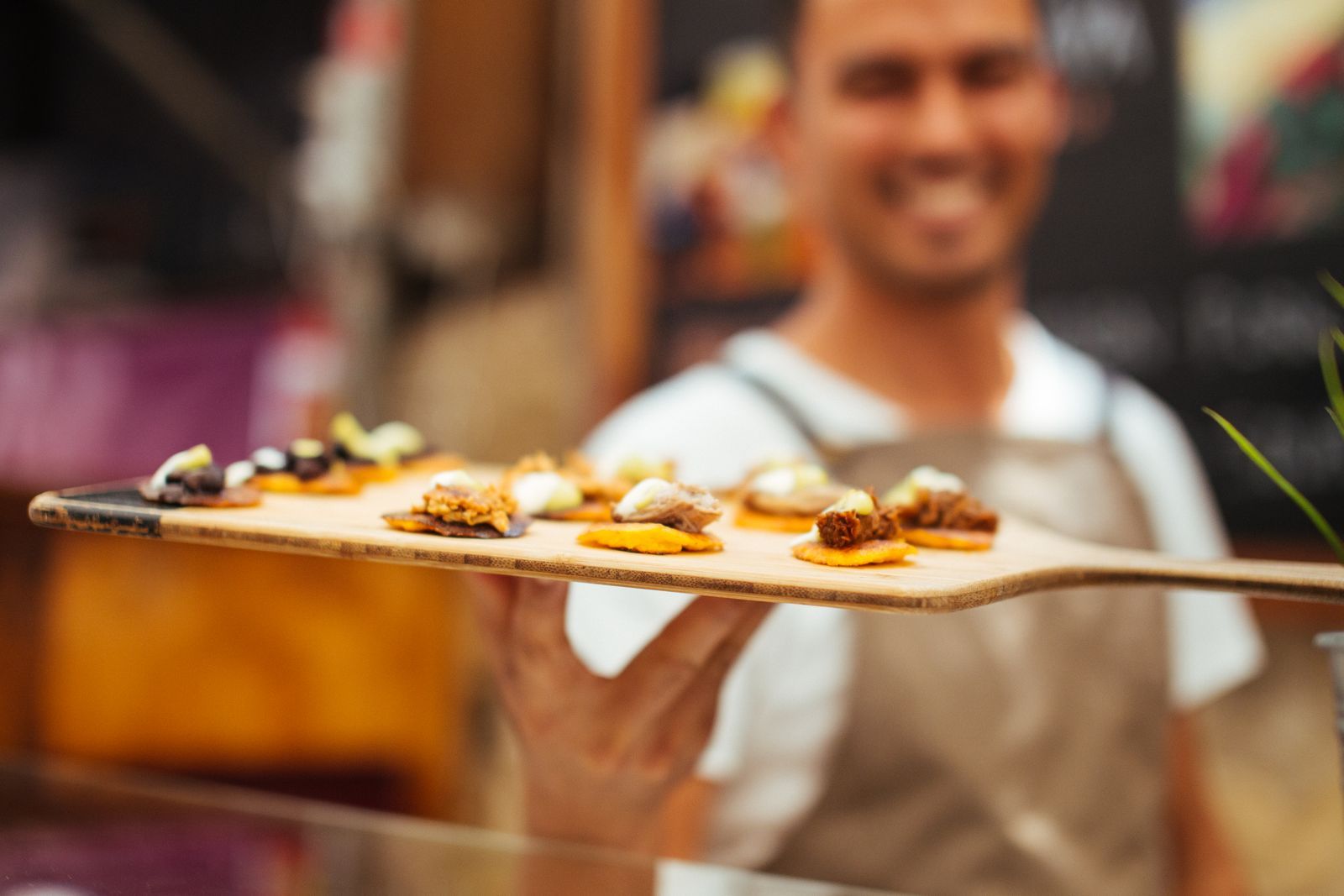 Staff member offering a tray of samples to visitors, a typical job for promoters in Abu Dhabi