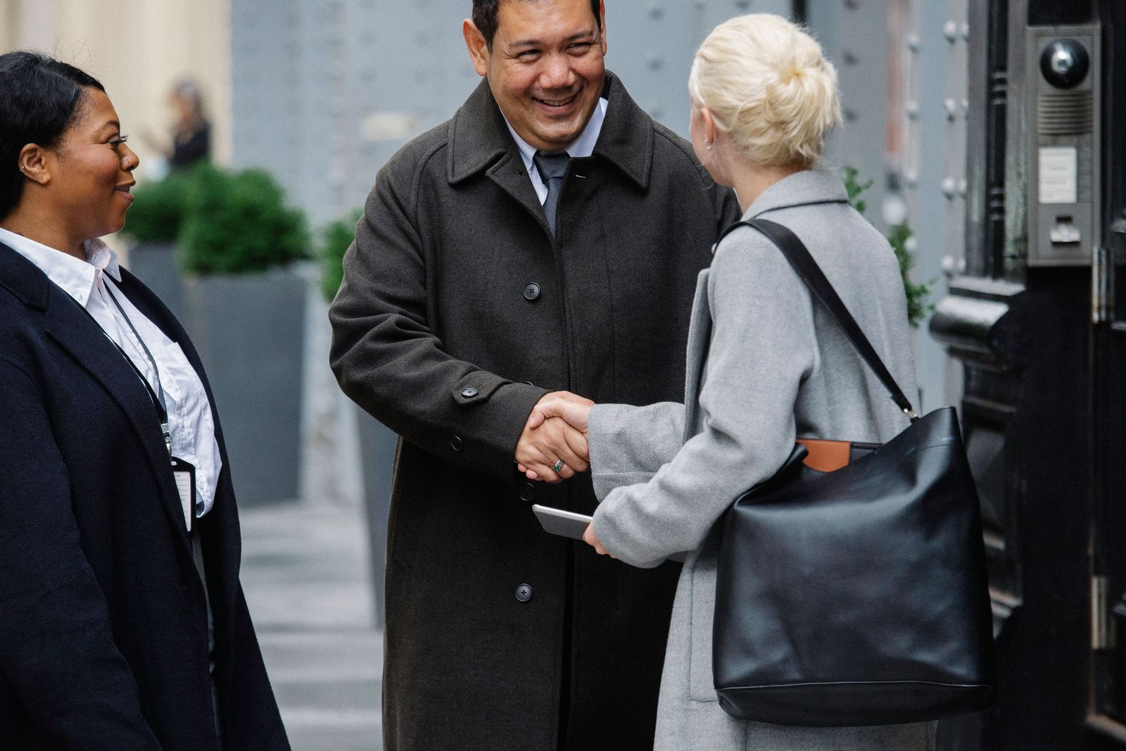 Usher in a dark suit and lanyard welcoming arriving guests at a venue entrance
