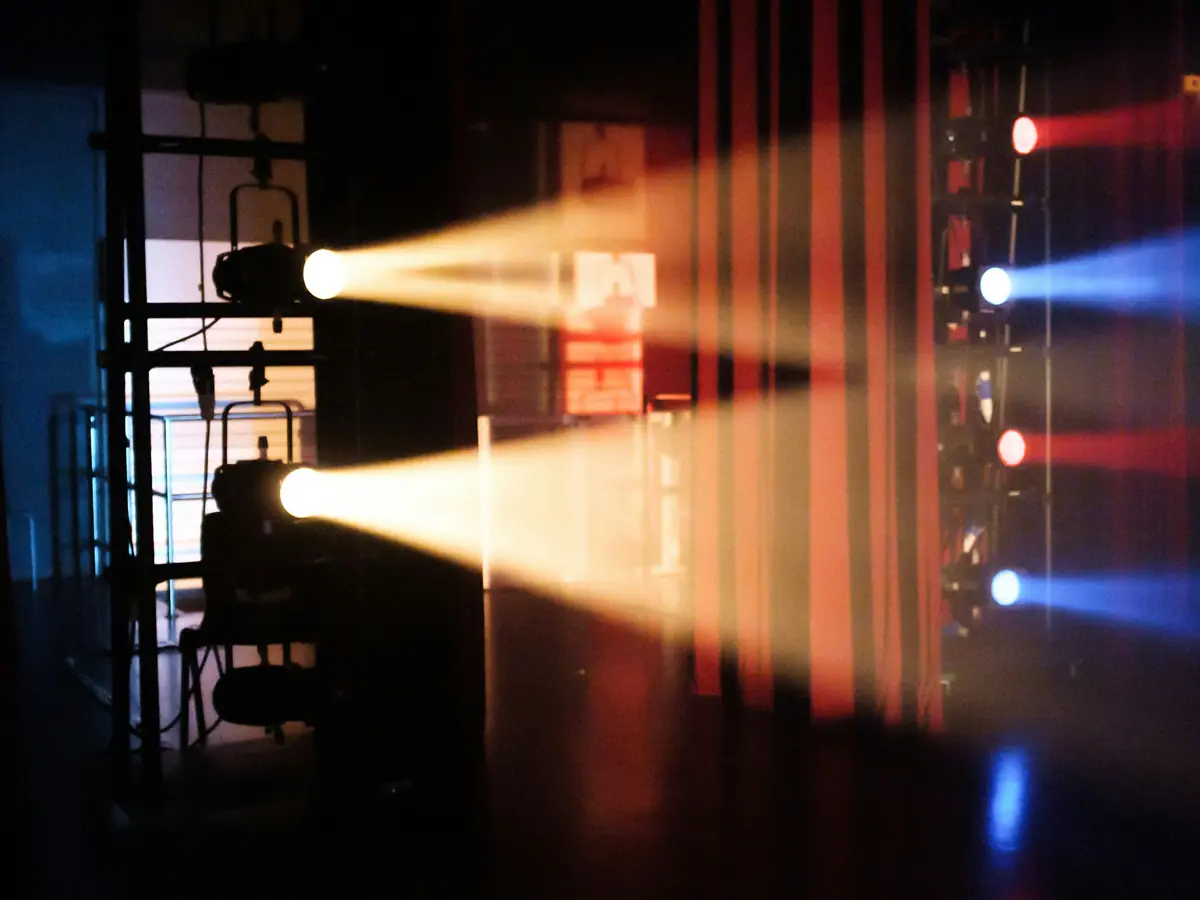 Stage lights shining across the wings from backstage