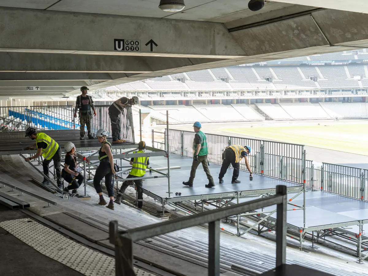 Crew building a raised stage platform inside a stadium